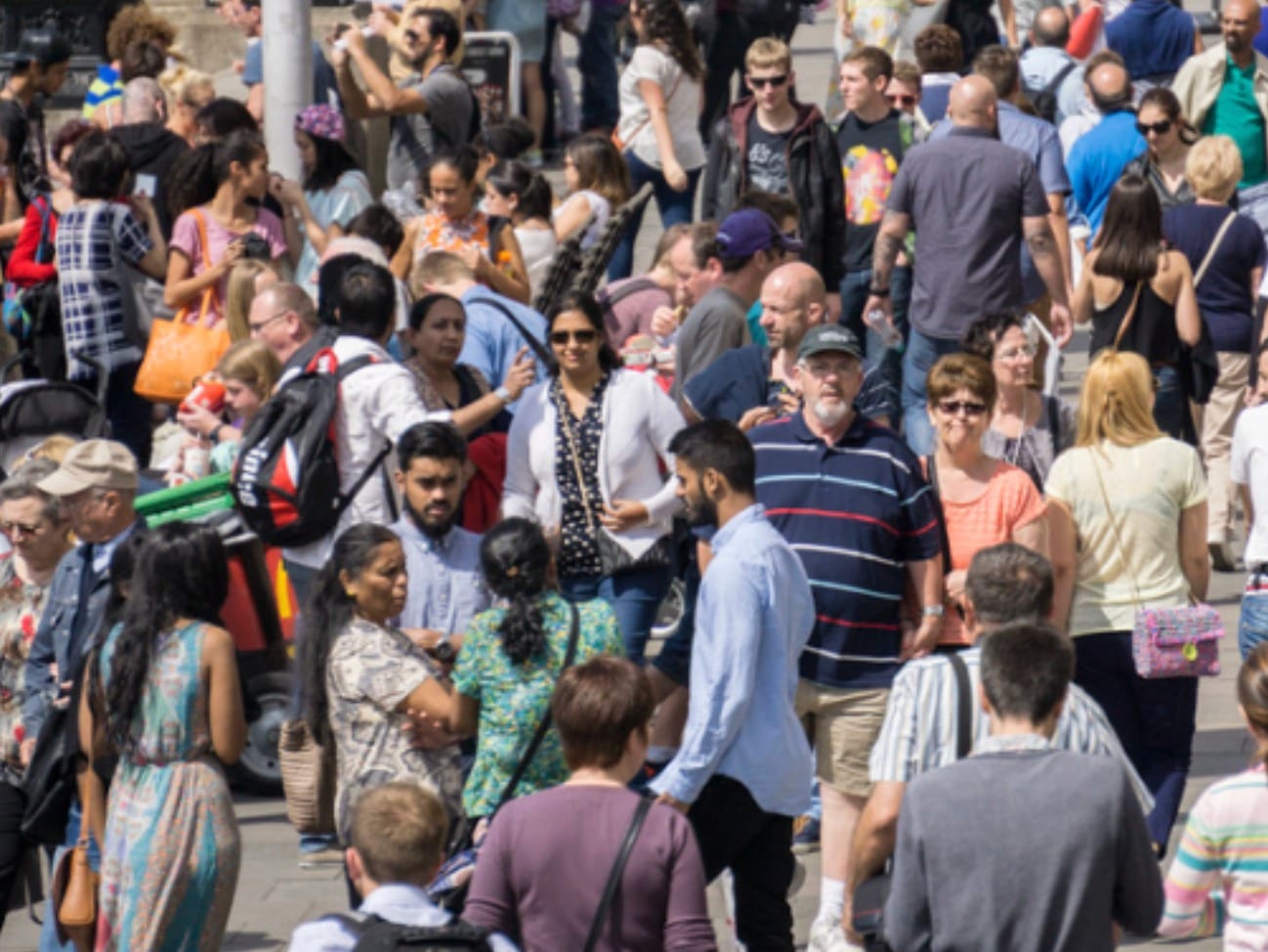 A dense crowd of people of all ages in a busy public street